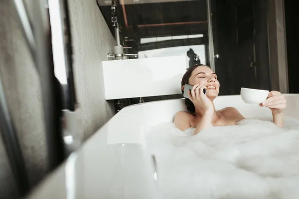 Fiatal nő beszélt telefonon, miközben figyelembe fürdő — Stock Fotó