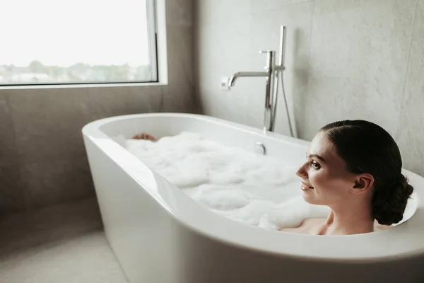 Jovem senhora sorrindo tomar banho de espuma relaxante — Fotografia de Stock