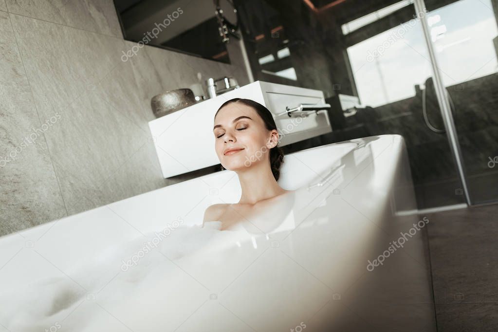 Young smiling lady taking relaxing bubble bath