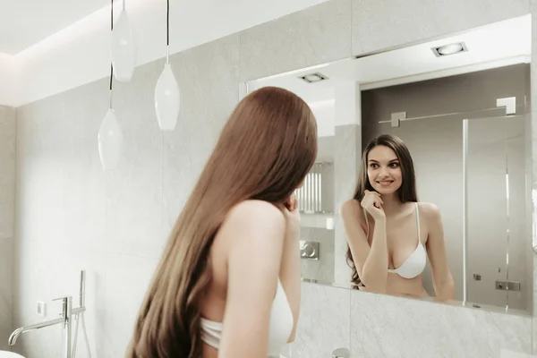 Optimistische Dame blickt im Badezimmer in den Spiegel — Stockfoto