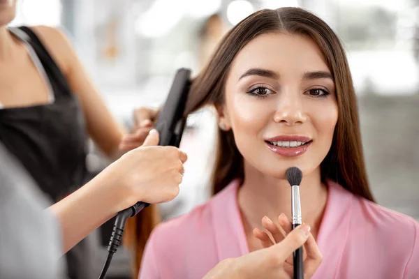 Senhora relaxada sorrindo enquanto esteticistas trabalhando em sua aparência — Fotografia de Stock