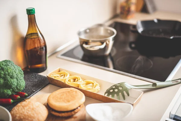 Pasta, spaghetti server, Hamburger broodjes en kookgerei in keuken — Stockfoto
