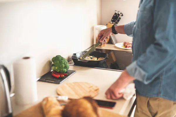 Ο άνθρωπος χρησιμοποιώντας λαβίδα, ενώ το μαγείρεμα κολοκυθάκια στην κουζίνα — Φωτογραφία Αρχείου