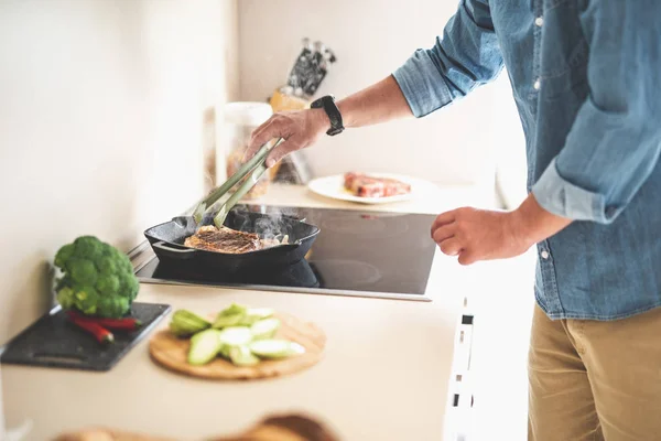Ο άνθρωπος που μαγείρεμα νόστιμο ζουμερή μοσχαρίσια μπριζόλα στην κουζίνα — Φωτογραφία Αρχείου