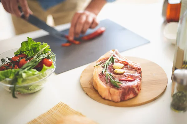 Stück Fleisch mit verschiedenen Zutaten und Mann Kochen auf verschwommenem Hintergrund — Stockfoto