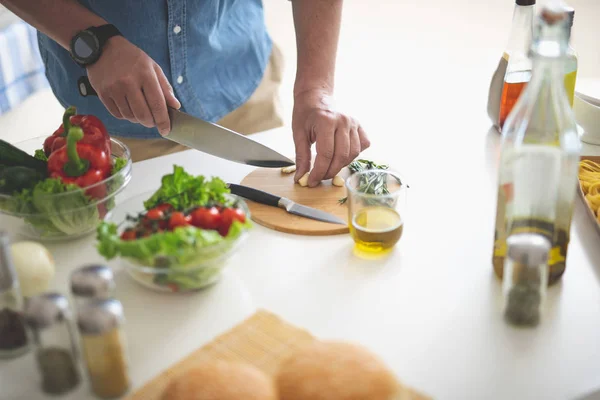 Hombre picando ajo con cuchillo en tabla de cortar — Foto de Stock