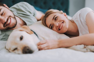 Hteir köpek ile yatakta yatan genç çift