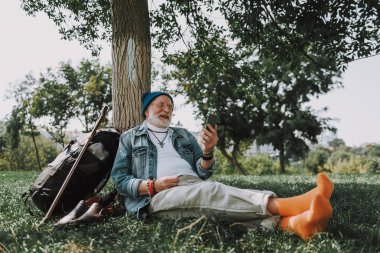 Çimenlerin üzerinde oturan ve seyir telefon komuta sizde