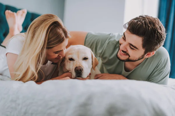 Alegre joven pareja descansando con su perro — Foto de Stock