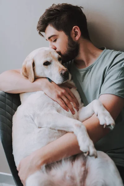 Příjemný mladý muž líbání jeho pes při vyjadřování lásky — Stock fotografie