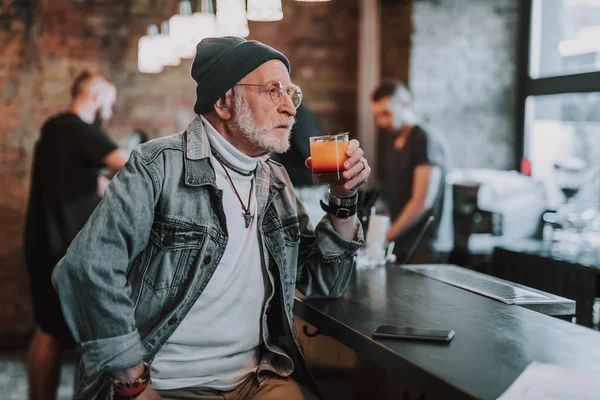 Élégant vieil homme tient un cocktail dans le bar — Photo