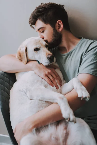 Jovem agradável beijando seu cão enquanto expressa amor — Fotografia de Stock