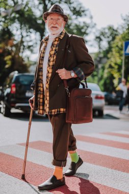 Yaşlı adam sokakta yürürken gülümseyen hipster