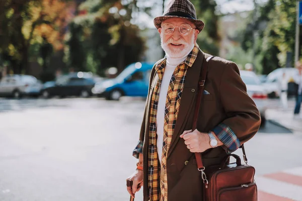 Улыбающийся старый мужчина, идущий через дорогу — стоковое фото