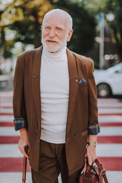 Stylish cheerful old man walking across the street