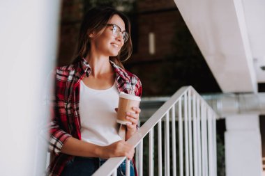 Uzağa bakarak ve gülümseyerek sıcak içecek çekici genç bir bayanla