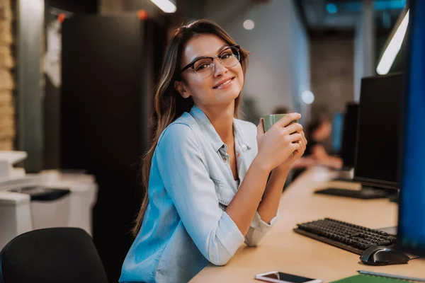 Hermosa chica en vasos sosteniendo la taza de café en el trabajo — Foto de Stock