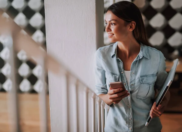 Hermosa mujer joven sosteniendo portátil y teléfono celular — Foto de Stock