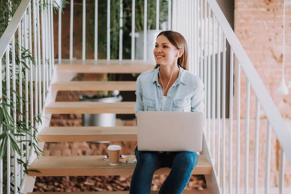 Charmante jonge dame luisteren muziek en het gebruik van laptop — Stockfoto