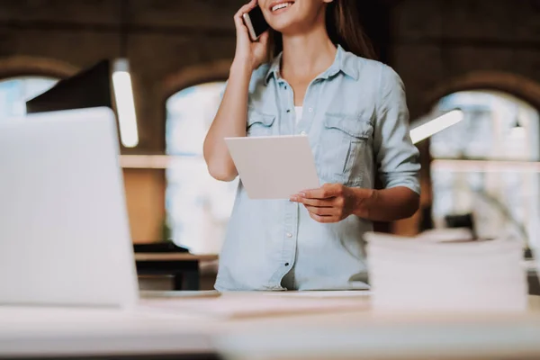 Charmante meisje houden blanco papier kaart en praten op mobiele telefoon — Stockfoto