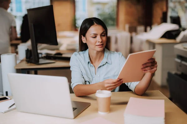 Schöne junge Frau liest Dokumente im Büro — Stockfoto