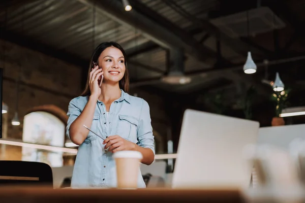 Vrolijke jongedame met telefoongesprek bij moderne kantoor — Stockfoto