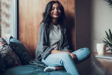 Bel kadar rahat pencere pervazına üzerinde oturan ve gülümseyen güzel Bayan