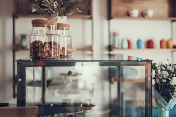 Laconic image of glass case with jars of cookies on it — Stock Photo, Image