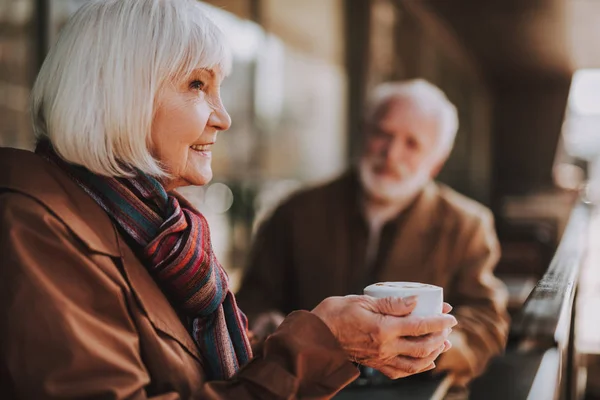 Senior senhora desfrutando de bebida quente enquanto passa o tempo com o marido no café ao ar livre — Fotografia de Stock