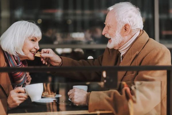 Vrolijke oude heer vervoederen aan zijn vrouw met heerlijke taart — Stockfoto