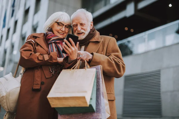 Belo casal de idosos usando celular na rua — Fotografia de Stock