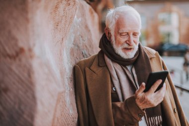 Şık yaşlı adam sokakta cep telefonu kullanarak