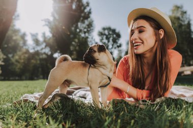 Gülümseyen kadın köpeğiyle ekose üzerinde yatıyor
