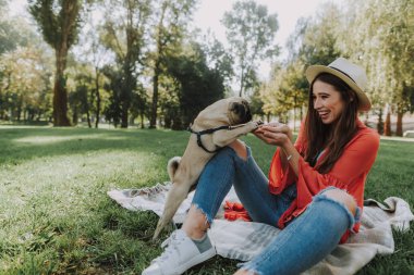 Genç kadın ekose üzerinde oturan ve onu köpek besleme