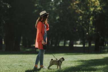 Genç kadın köpeğini güneşli Park ile yürüyor