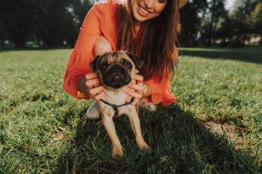 Genç gülümseyen kadın çimenlerin üzerinde köpeğiyle oturuyor