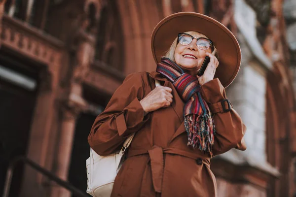 Encantadora anciana con sombrero hablando por celular en la calle —  Fotos de Stock