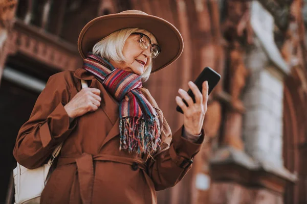 Stylowe stara kobieta w kapeluszu, przy użyciu telefonu komórkowego na ulicy — Zdjęcie stockowe