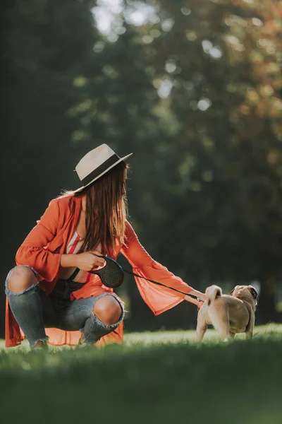 Jovem senhora está sentada na grama com seu cão — Fotografia de Stock