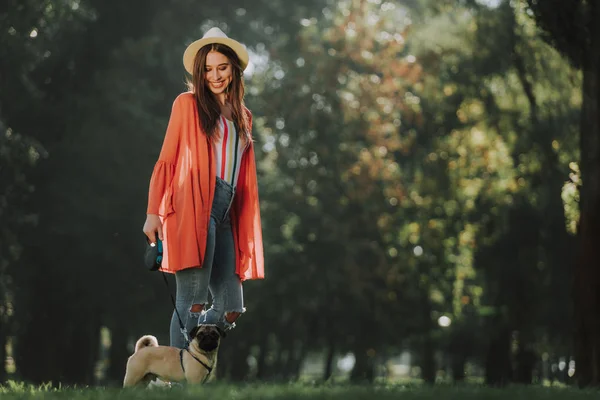 Jeune femme est debout dans le parc avec son chien — Photo