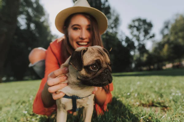 Ładna pani w kapeluszu to przytulanie jej pug puppy — Zdjęcie stockowe