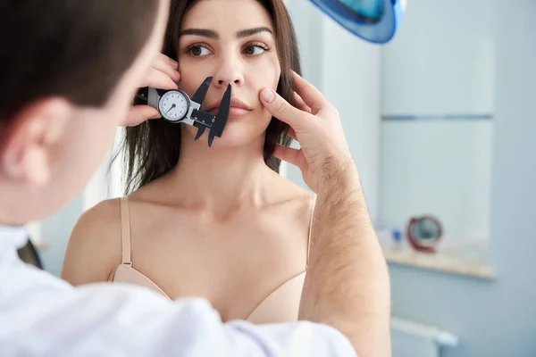 Médico midiendo la cara de paciente femenina con pinzas — Foto de Stock