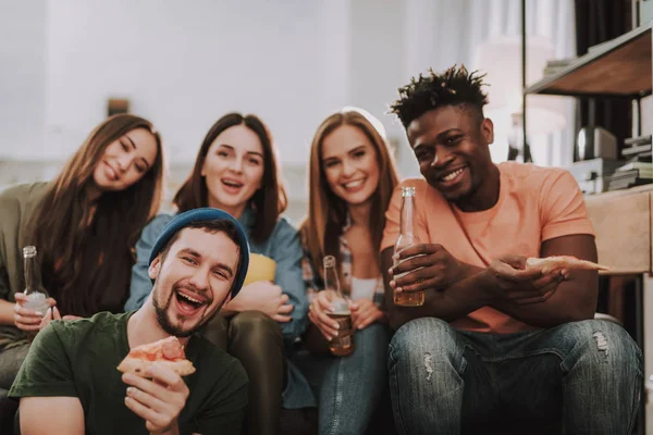 Fröhliche junge Leute essen und trinken, während sie Zeit miteinander zu Hause verbringen — Stockfoto