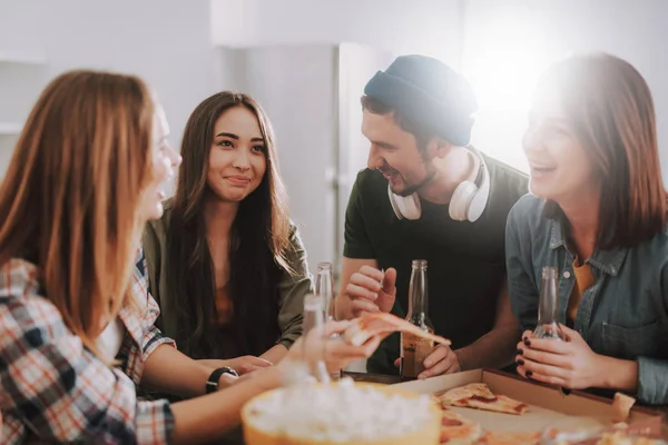 Jóvenes alegres divirtiéndose mientras disfrutan de pizza y bebidas — Foto de Stock