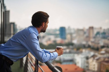 Bir erkek işçinin office balkonda kahve içme
