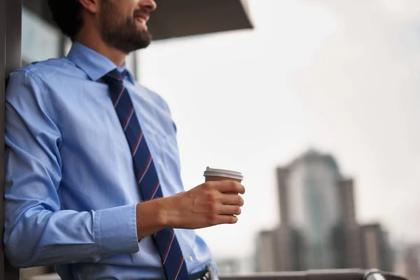 One male worker drinking coffee on office balcony