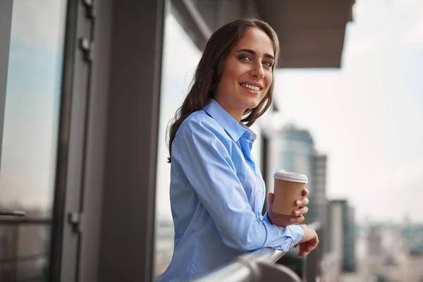 Женщина-работница пьет кофе на балконе офиса — стоковое фото