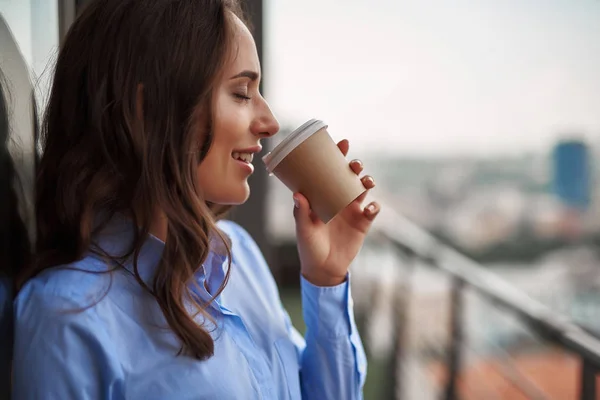 Жінка-працівник п'є каву на офісному балконі — стокове фото