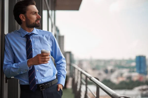 Um trabalhador do sexo masculino beber café na varanda do escritório — Fotografia de Stock