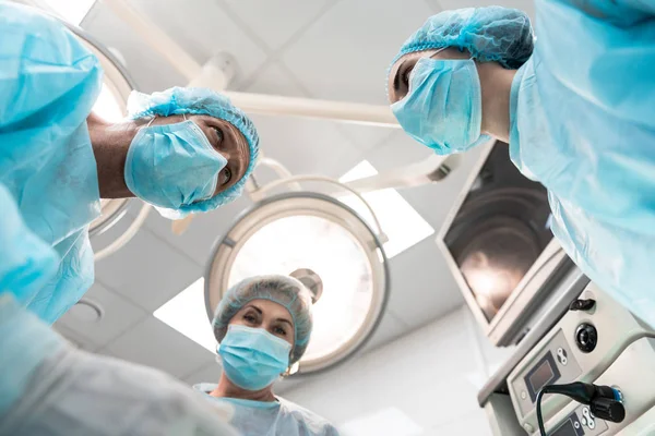 Médicos profesionales mirándose mientras usan máscaras en el trabajo — Foto de Stock